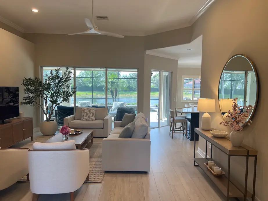 Bright living room with cream sofas, a ceiling fan and a lake view