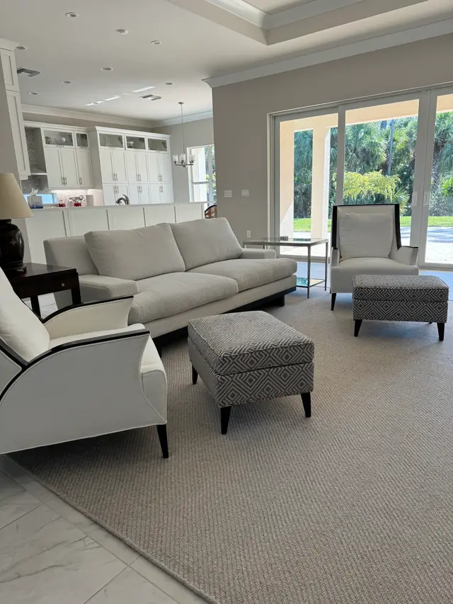 Pale living room with a grey sectional, ottoman and sliding doors to a garden